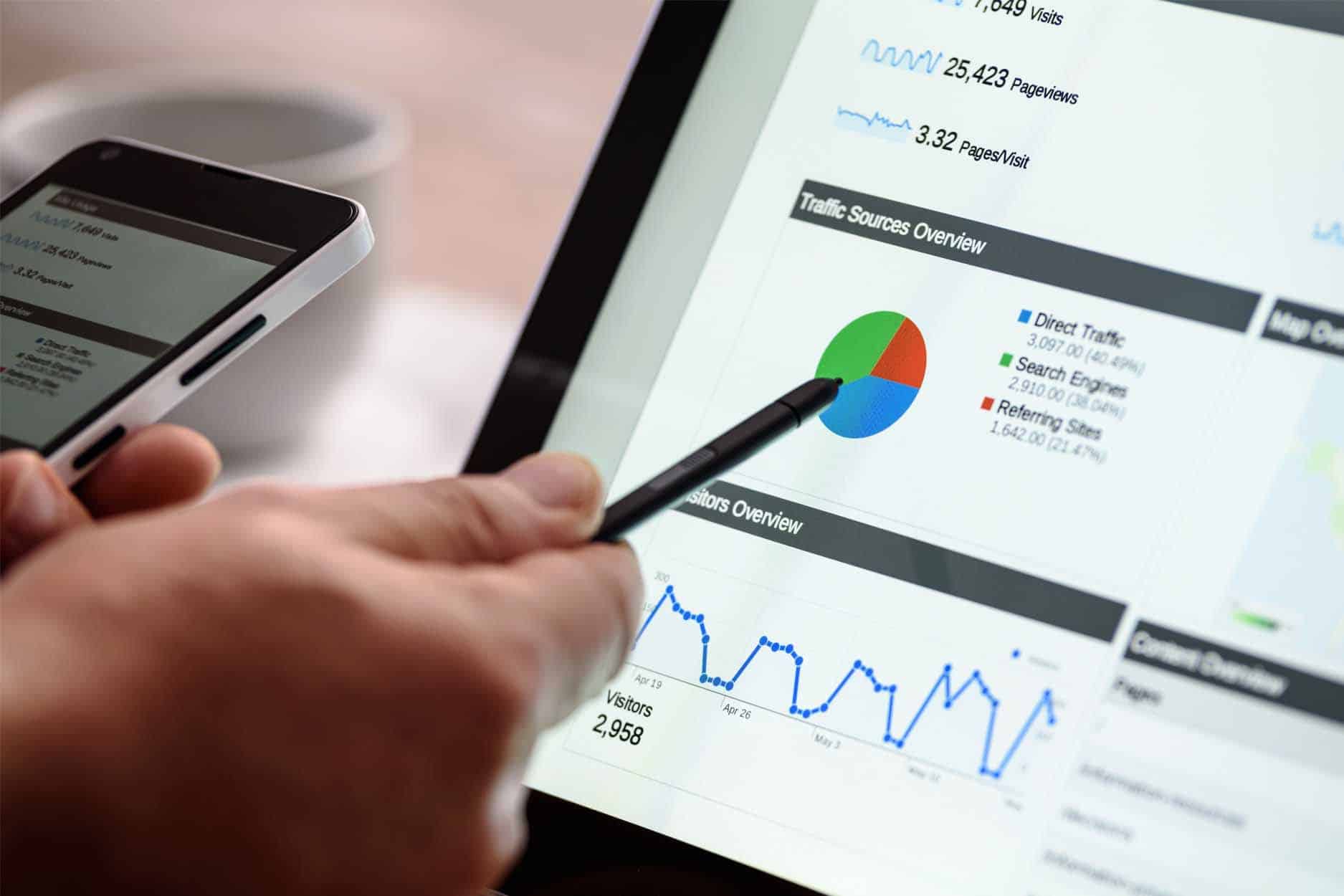 hand with pen in it pointing to tablet with seo analytics